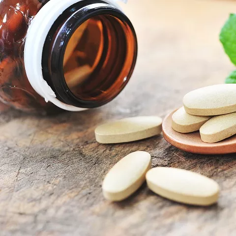 Pills spilled on a table with pill bottle in background